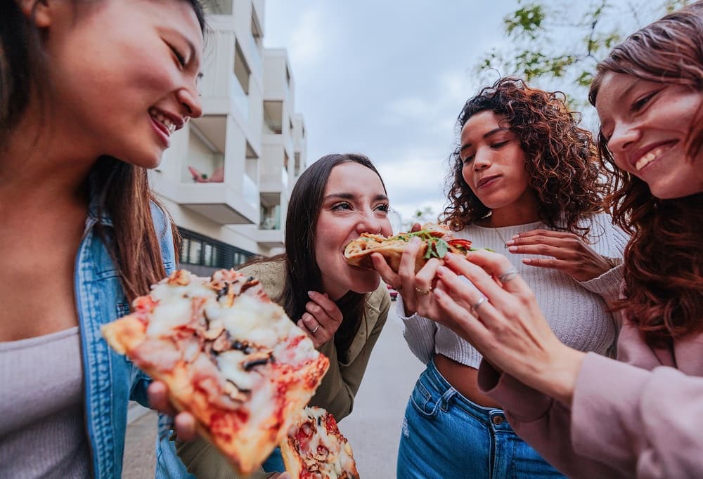 Friends sharing pizza together outdoors