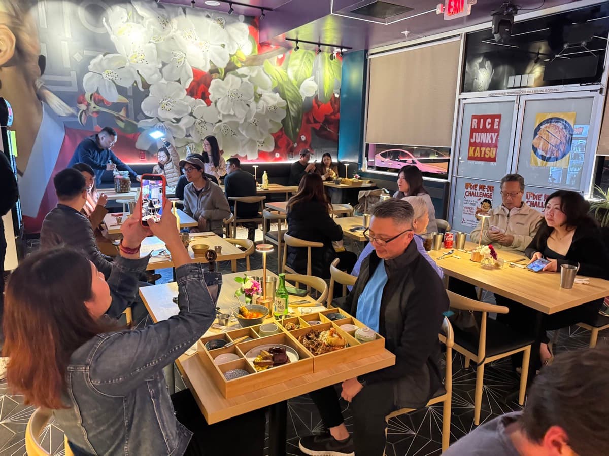 A full dining room at Rice Junky Katsu with a guest photographing their bento