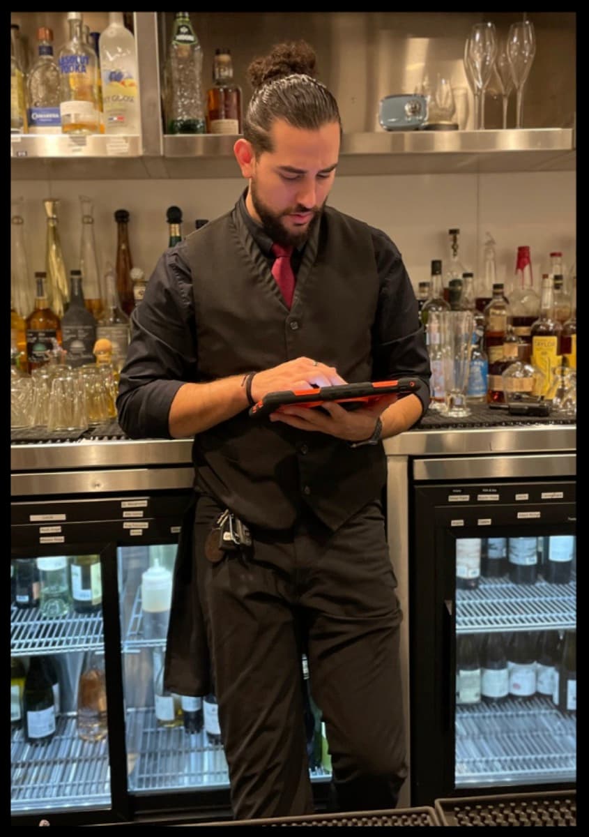 A bartender running a quick training drill on a tablet behind the bar