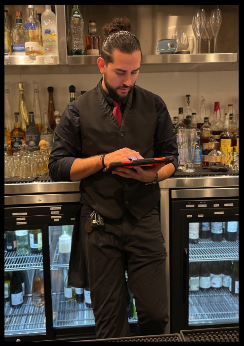 A bartender running a quick training drill on a tablet behind the bar